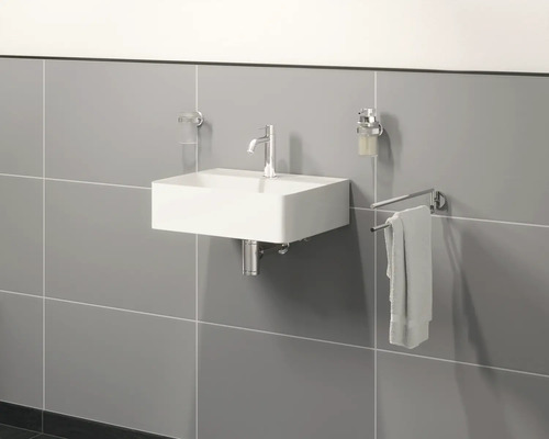 Nástěnné umyvadlo s vodovodní baterií, dávkovačem mýdla, ručníkem a kelímkem na zubní kartáčky v koupelně