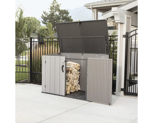 Otevřený plastový box na nářadí s uloženým dřevem na zahradě.