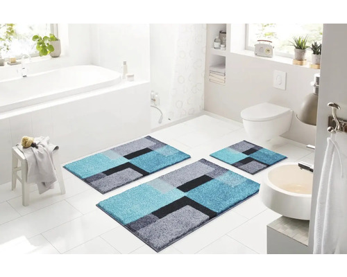 Koupelna s vanou, toaletou a umyvadlem a sadou koupelnových předložek se geometrickým vzorem skládající se ze tří kusů