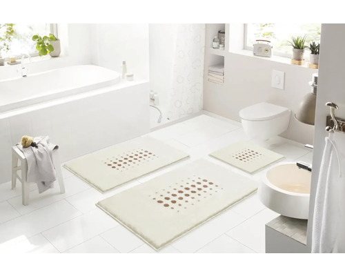 Světlá koupelna s vanou, umyvadlem, toaletou a sadou tří koupelnových předložek s tečkovaným vzorem