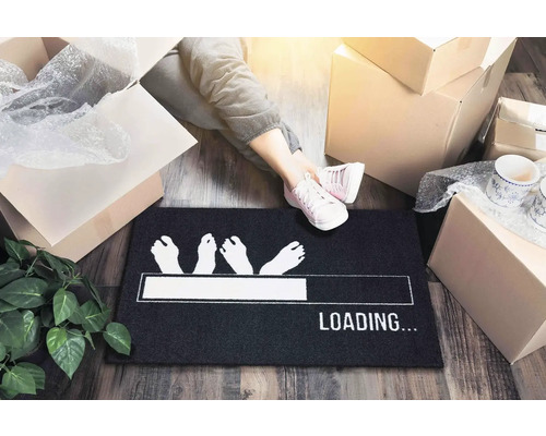 Scéna se stěhovacími krabicemi a osobou s botami na rohožce s vytištěným ukazatelem průběhu načítání