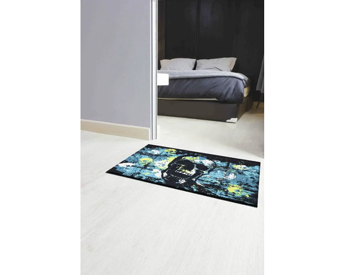 Pokoj s postelí a rohožkou s motivem lebky