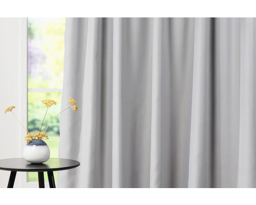 Ozdobné šály před oknem se stolem a vázou s květinami