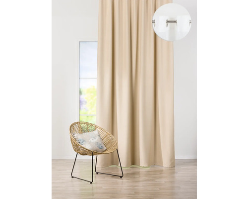 Béžový závěs s očky vedle ratanového křesla ve světlé místnosti.