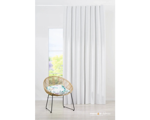 Interiérový snímek obývacího pokoje s bílým závěsem, ratanovým křeslem a květinovým polštářem před oknem