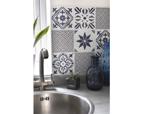 Dřez s vodovodní baterií před stěnou s ozdobnými obkladačkami v kuchyni.