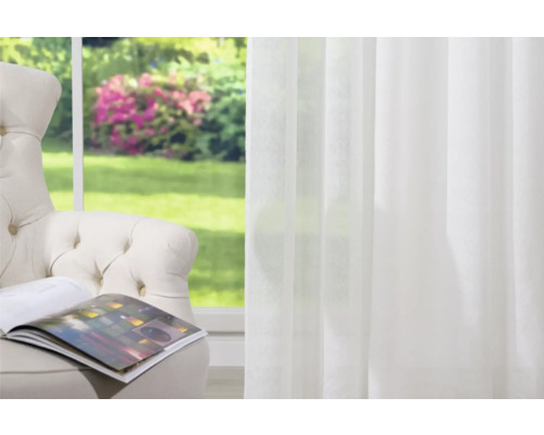 Scéna s křeslem, otevřenou knihou a bílým průhledným závěsem před oknem