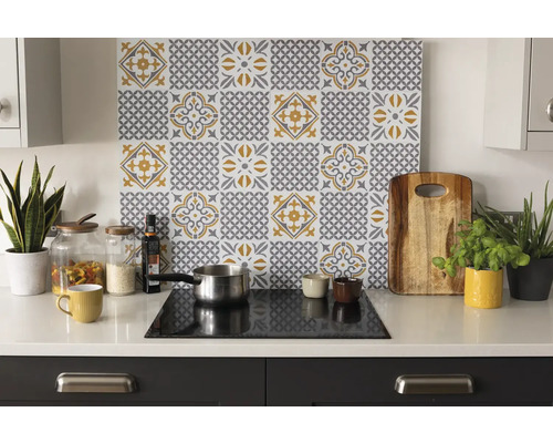 Kuchyňská scéna s obkladem se vzorem dlaždic ve žluté a šedé barvě nad varnou deskou