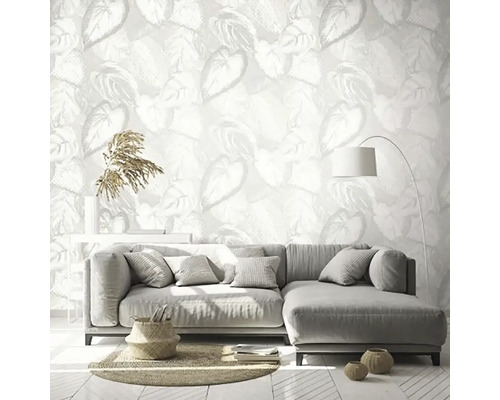 Obývací pokoj s nástěnnou tapetou s motivem listů, šedou pohovkou a stojací lampou.