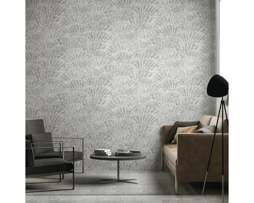 Obývací pokoj s šedou tapetou se vzorem vějíře, pohovkou, křesly a lampou.