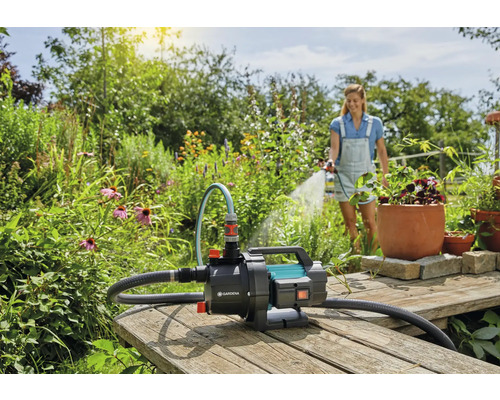 Zahradní scéna s ženou zalévající rostliny zahradním čerpadlem Gardena