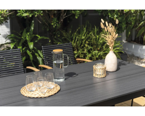 Zahradní scéna se stolem, židlemi, sklenicemi, karafou na vodu, svíčkou a dekorací.