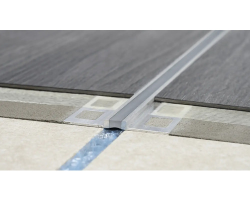 Detailní záběr instalace dilatačního profilu mezi dvě podlahové krytiny