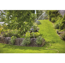 Zahrada se zavlažovačem trávníku na kamenném podstavci zavlažujícím trávník.
