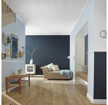 Světlá místnost s gaučem, dřevěnou lavicí, schodištěm a dekoracemi