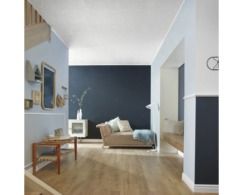 Světlá místnost s gaučem, dřevěnou lavicí, schodištěm a dekoracemi