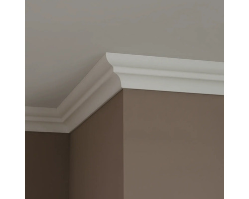 Roh místnosti s bílou ozdobnou lištou mezi stěnou a stropem