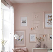 Dekorativní obývací pokoj s motivem motýlů, včetně zarámovaných obrázků, nástěnných dekorací a odpovídajících doplňků.