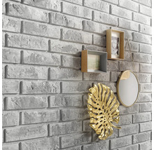 Nástěnná dekorace s kamenným vzhledem a dekorativními prvky, jako jsou rámečky na fotografie, zrcadlo a listová ozdoba