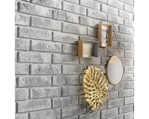 Nástěnná dekorace s kamenným vzhledem a dekorativními prvky, jako jsou rámečky na fotografie, zrcadlo a listová ozdoba