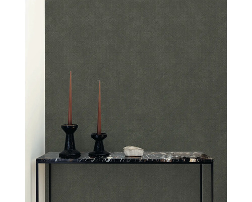 Detailní záběr místnosti s šedou vliesovou tapetou, dvěma svícny se svíčkami a stolem s mramorovou deskou.