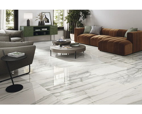 Světlý obývací pokoj s bílými dlaždicemi v mramorovém vzhledu, pohovkou a odkládacím stolkem.