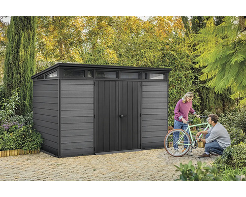 Šedá kůlna s horním světlem a dvěma lidmi opravujícími kolo