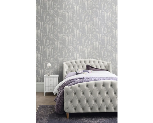 Ložnice s čalouněnou postelí, nočním stolkem a vzorovanou tapetou s květinovým vzorem