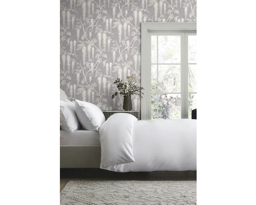 Ložnice s ložním prádlem, tapetou s květinovým vzorem a denním světlem