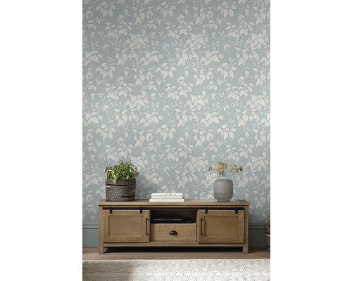 Obývací pokoj se světle modrou tapetou s listovím a dřevěnou skříňkou