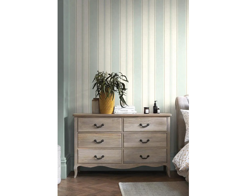 Světlá ložnice s pruhovanou tapetou a komoda se šesti zásuvkami