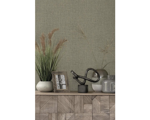 Design obývacího pokoje s textilní tapetou, okrasnými travinami, rámem na fotografie a dekorativními prvky na dřevěné skříni.