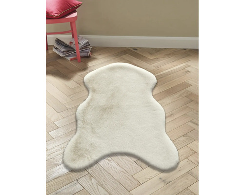 Světle barevný koberec z ovčí kůže na dřevěné podlaze