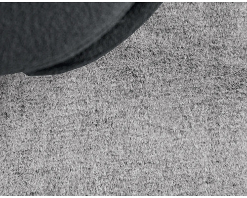 Detailní záběr koberce s částí sedacího nábytku.