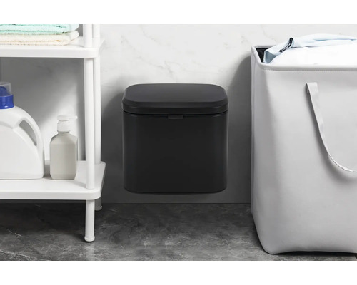 Nástěnný odpadkový koš vedle koše na prádlo a police