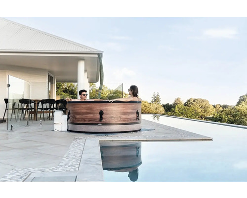 Pár relaxuje ve vířivce na terase vedle bazénu.