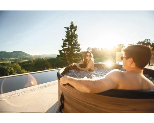 Pár relaxuje v koupací kádi s výhledem do krajiny