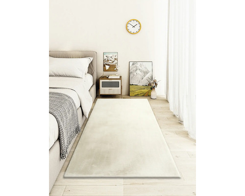 Světlá ložnice s postelí, nočním stolkem a dlouhým obdélníkovým kobercem