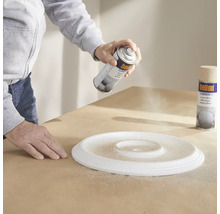 Osoba stříká barvou ve spreji stropní rozetu.