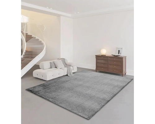 Obývací pokoj s šedým kobercem, pohovkou, schodištěm a komodou