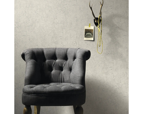 Šedé křeslo před strukturovanou stěnou s dekorací