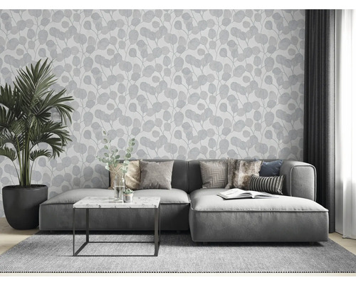 Obývací pokoj s šedou pohovkou, pokojovou rostlinou a tapetou s listovým vzorem