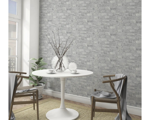 Světlá místnost s tapetou s motivem cihel, stolem a židlemi