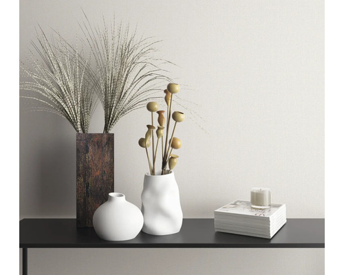 Dekorativní scéna s vázami, sušenými květinami, svíčkou a knihou na konzole