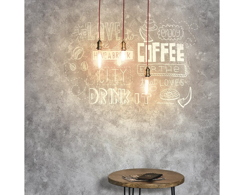 Tři závěsná světla nad malým stolem před stěnou s motivy kávy