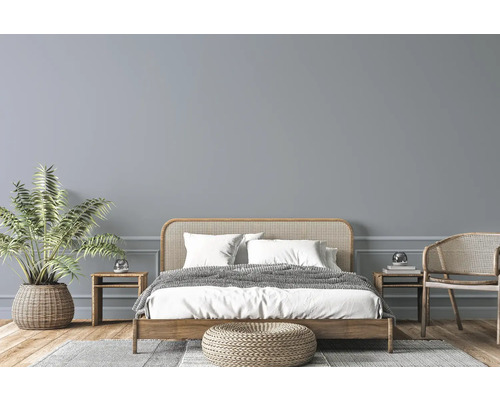 Světlá ložnice s dřevěnou postelí, proutěným nábytkem, pokojovou rostlinou a kobercem