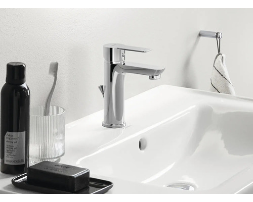 Detailní pohled na umyvadlo s baterií, mýdlo, kelímek na zubní kartáček a držák na ručníky