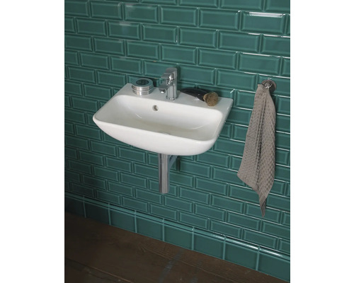 Umyvadlo v koupelně s kohoutkem a ručníkem před obkládačkami