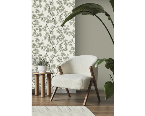 Scéna s květinovou tapetou, křeslem, odkládacím stolkem, kobercem a pokojovou rostlinou.