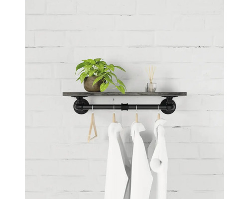 Nástěnná police s trubkovou tyčí a ramínky na oblečení na cihlové zdi